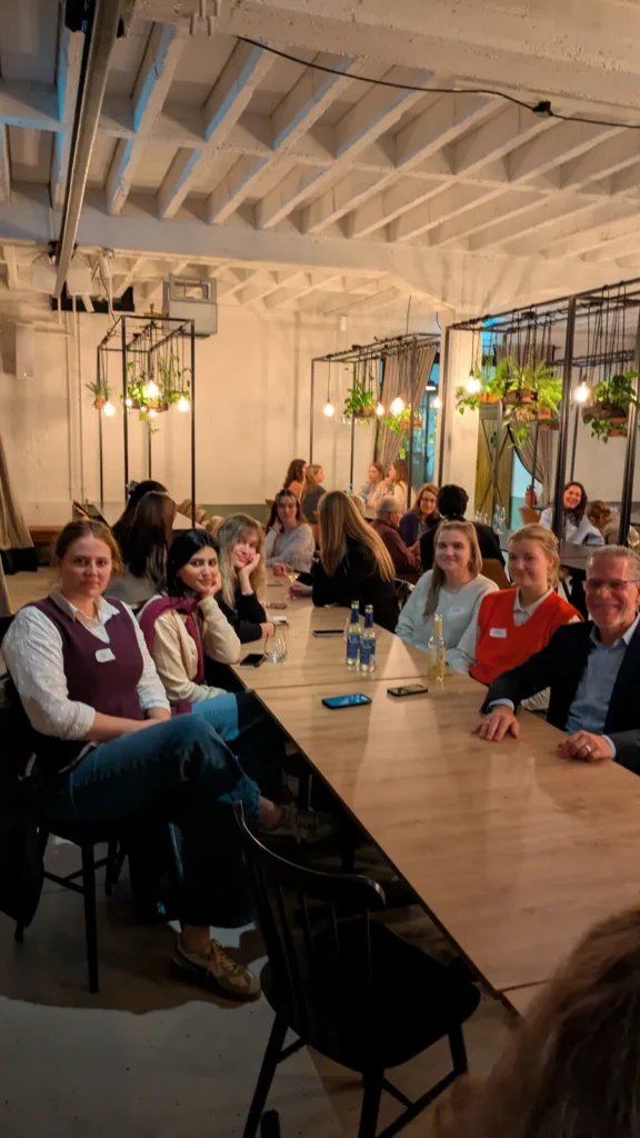 Studierende und Gäste an einer langen Tafel beim Get-together 2025