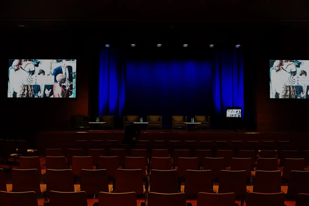 Die leere Aula am Bildungscampus mit blauem Bühnenvorhang und Bildschirmen